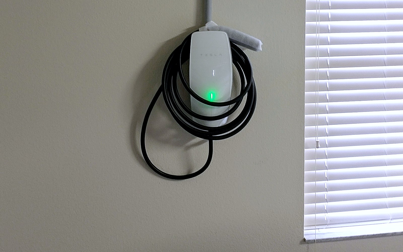 Tesla Wall Connector mounted on a residential wall with conduit run to the panel